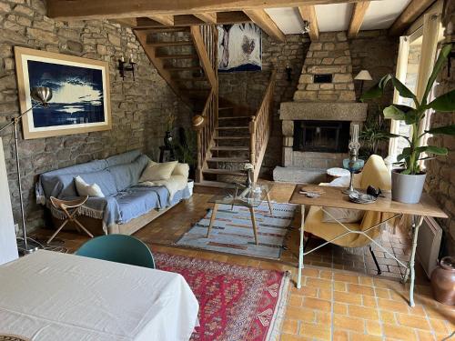 un salon avec un canapé et une cheminée dans l'établissement TY MAEN - Authentique moulin du 18ème proche mer, à Plourin