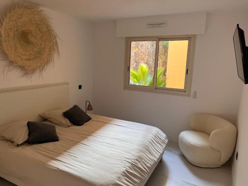 een slaapkamer met een bed met een stoel en een raam bij Proche Monaco luxueux appartement vue mer in Cap d'Ail