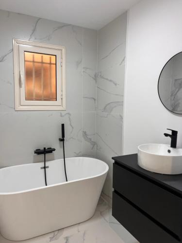 een witte badkamer met een bad en een wastafel bij Proche Monaco luxueux appartement vue mer in Cap d'Ail