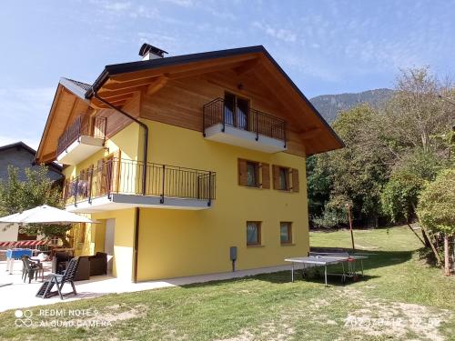a yellow house with a balcony and a table at Baita Figliezzi in Castello Tesino