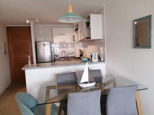 a kitchen with a glass table and some chairs at Departamento playa La Herradura in Coquimbo