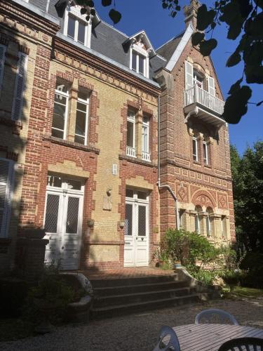 - un grand bâtiment en briques avec une porte blanche et un balcon dans l'établissement Studio in a 19th century villa with parking, à Villers-sur-Mer