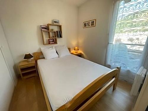 un lit dans une chambre avec une grande fenêtre dans l'établissement Super appartement en résidence proche du centre, à Briançon
