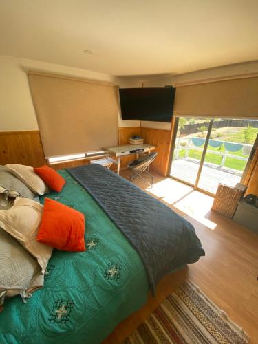 a bedroom with a bed with orange pillows and a desk at Casa Costa Zapallar in Catapilco