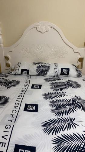 ein weißes Bett mit schwarzweißer Bettwäsche und Kissen in der Unterkunft PINEVALLEY APT .SUITE 3A 