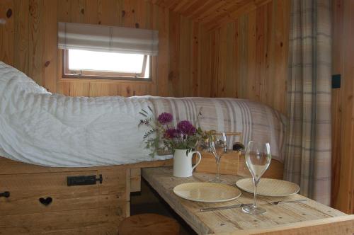 a bedroom with a bed with two glasses and a table at River Meadow Retreat in Uffculme