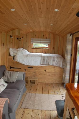 um quarto com uma cama e um sofá num quarto de madeira em River Meadow Retreat em Uffculme
