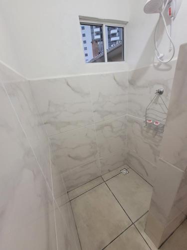 uma casa de banho com um chuveiro com azulejos brancos em Suíte 2 com sala em Lages