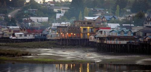a group of houses on the shore of a body of water at Palafito 1326 Hotel Boutique Chiloé in Castro