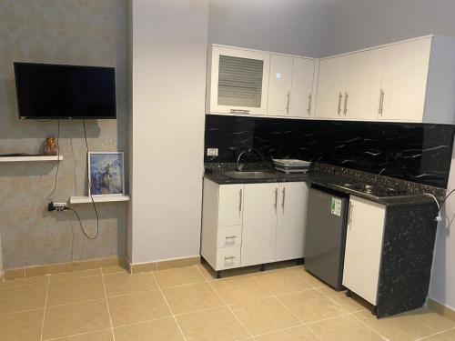 a kitchen with white cabinets and a black counter top at Alfayrouz house in Hurghada