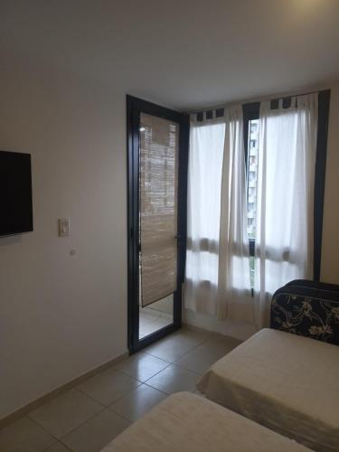 a room with two beds and a window and a television at Monoabiente amoblado Gobernantes Guzmán in Río Cuarto