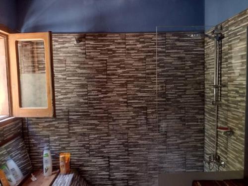 uma casa de banho com um chuveiro e uma parede de tijolos em Posada Los Nogales em Junín