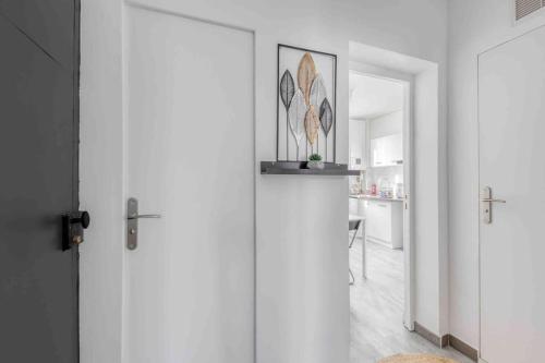 a white room with a door and a kitchen at Appartement Cosy I Proche de la Porte de Versailles Paris in Malakoff