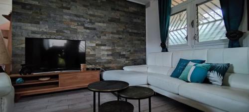 a living room with a white couch and a tv at casahibiscus in Fort-de-France