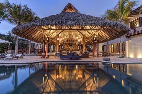 een grote rieten parasol naast een zwembad bij Casa Koko NEW 6-Suite Ocean-View Luxury Villa in Punta Mita