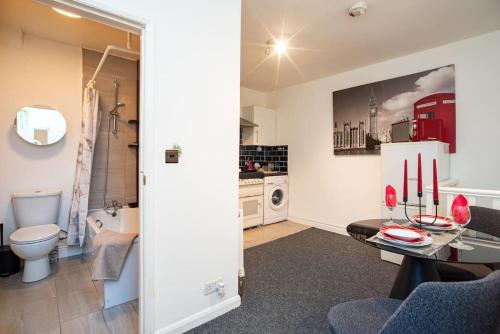 a living room with a table and a bathroom at Watford Central Serviced Apartments in Watford