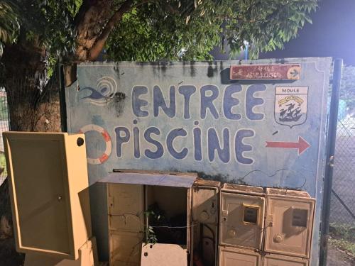a sign for an entrance to an appliance with an arrow at Studio cosy les pieds dans l'eau à l'autre bord in Le Moule