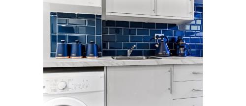 een keuken met een wastafel en een blauwe tegelmuur bij Comfortable and Stylish 1 BR flat - Sleeps 2 in Londen