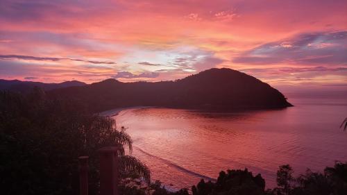a sunset over a body of water with a mountain at Casa com vista a praia da Barra do Sahy in Barra do Sahy