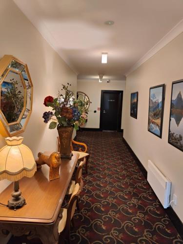 a hallway with a table and a vase of flowers at Gateway Motor Inn in Masterton