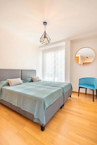 a bedroom with a large bed and a blue chair at Serene Haven Retreat - Madeira Island in Caniço