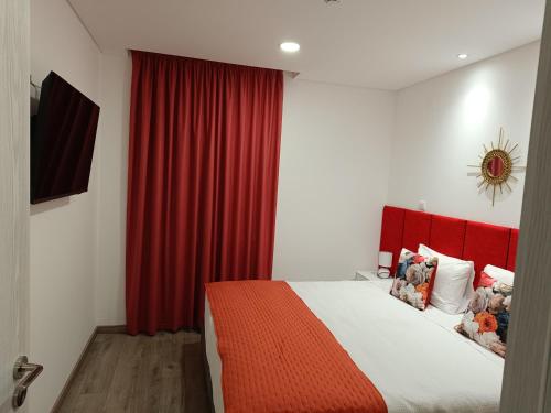 sypialnia z czerwoną zasłoną i łóżkiem w obiekcie Garden House Fundão - Suíte 202 com varanda w mieście Fundão