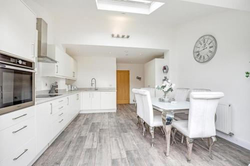 a kitchen with white cabinets and a table and chairs at Modern contemporary with parking in Hough Green