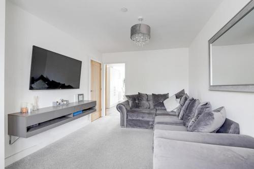 a living room with a gray couch and a flat screen tv at Modern contemporary with parking in Hough Green
