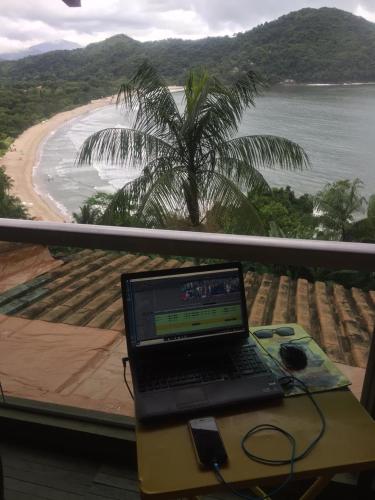 a laptop computer sitting on a table with a view of a beach at Casa com vista a praia da Barra do Sahy in Barra do Sahy