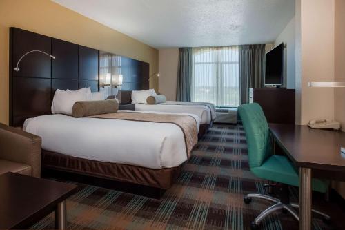 a hotel room with two beds and a desk at Wingate By Wyndham - Orlando International Airport- Free Hot Breakfast in Orlando