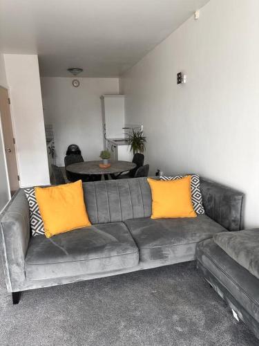 a leather couch with two yellow pillows in a living room at Recently Refurbished Apt central MK FREE PARKING in Milton Keynes