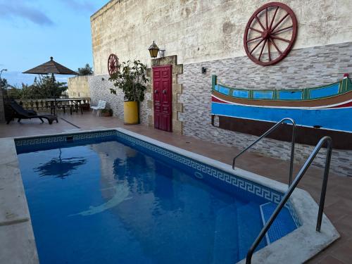 a swimming pool with a boat on the side of a building at Tal-Bir Farmhouse in Nadur