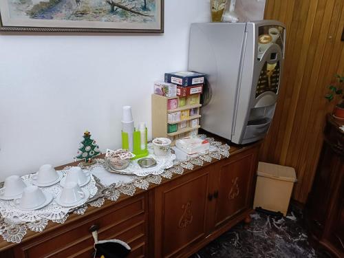 a counter with a refrigerator and a table with cups and dishes at Domus Cesena in Cesena