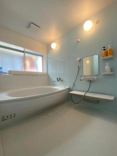 a white bathroom with a tub and a window at Aqua Beach House Sotoura - 1min walk to Sotoura Beach! in Shimoda