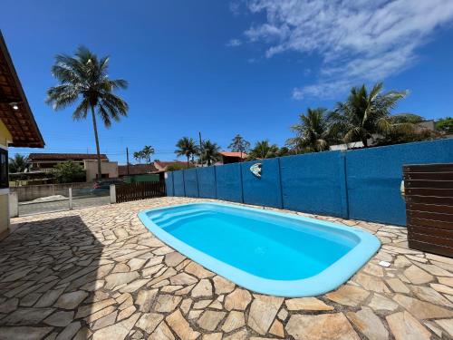 a blue swimming pool in a backyard with a fence and palm trees at Chalé Master Caraguatatuba cond Alto Padrão Massaguaçu in Caraguatatuba