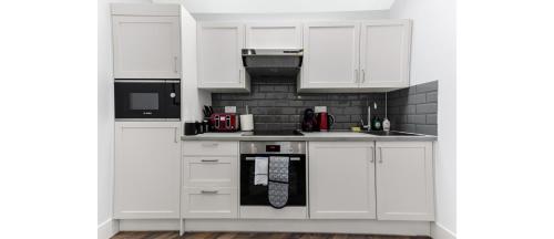a white kitchen with white cabinets and appliances at Newly Renovated 1BD Flat Perfect for Travellers in Romford
