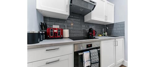 a kitchen with white cabinets and red appliances at Newly Renovated 1BD Flat Perfect for Travellers in Romford