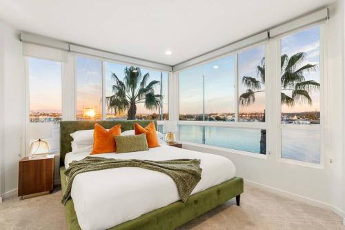 Schlafzimmer mit einem großen Fenster und einem Bett mit orangefarbenen Kissen in der Unterkunft Skyline Oasis: Luxe 3-Floor Waterfront Penthouse in Los Angeles
