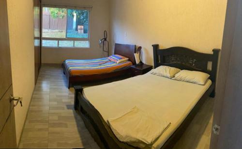 two twin beds in a room with a window at Finca El Balmoral in Tocaima