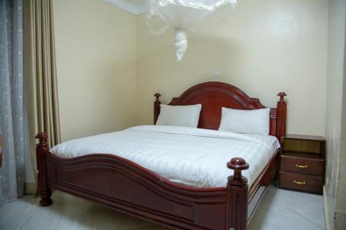 Bett mit einem Kopfteil aus Holz in einem Schlafzimmer in der Unterkunft Eziana palm hotels 