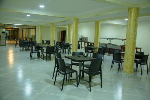 ein Restaurant mit Tischen und Stühlen in einem Zimmer in der Unterkunft Eziana palm hotels 