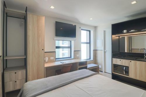 a bedroom with a bed and a desk and a sink at Housi Paulista in Sao Paulo