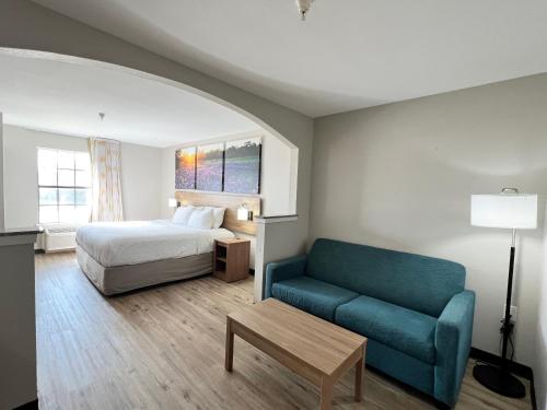 a hotel room with a bed and a couch at Days Inn by Wyndham Dallas Plano in Plano