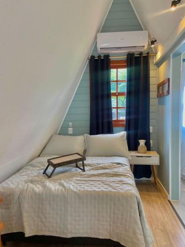 Un dormitorio con una cama con un banco. en Chalé Pé do Morro, en Penha