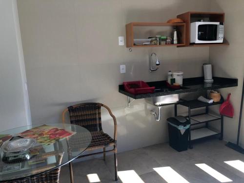 a small kitchen with a glass table and a microwave at Studio Carini in Curitiba
