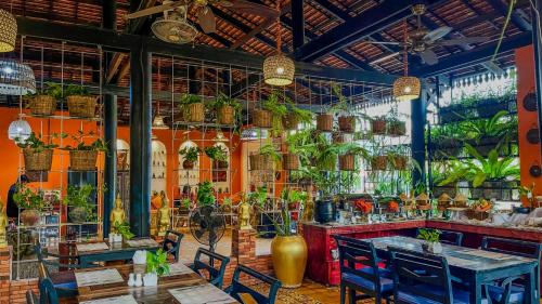 a restaurant with tables and chairs and potted plants at Residence Indochine D'angkor in Siem Reap