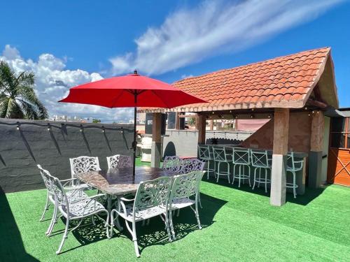 einen Tisch und Stühle mit einem roten Regenschirm auf dem Gras in der Unterkunft Luxury village on the 5th avenue with private rooftop in Playa del Carmen