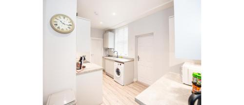 a white kitchen with a clock on the wall at Hassle-Free & Handsome Brand-New 3-Bed Home in Manchester