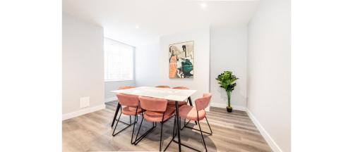 Un comedor con una mesa blanca y sillas naranjas. en Hassle-Free & Handsome Brand-New 3-Bed Home, en Mánchester