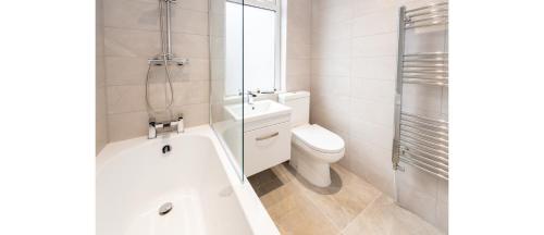 a bathroom with a tub and a toilet and a shower at Hassle-Free & Handsome Brand-New 3-Bed Home in Manchester